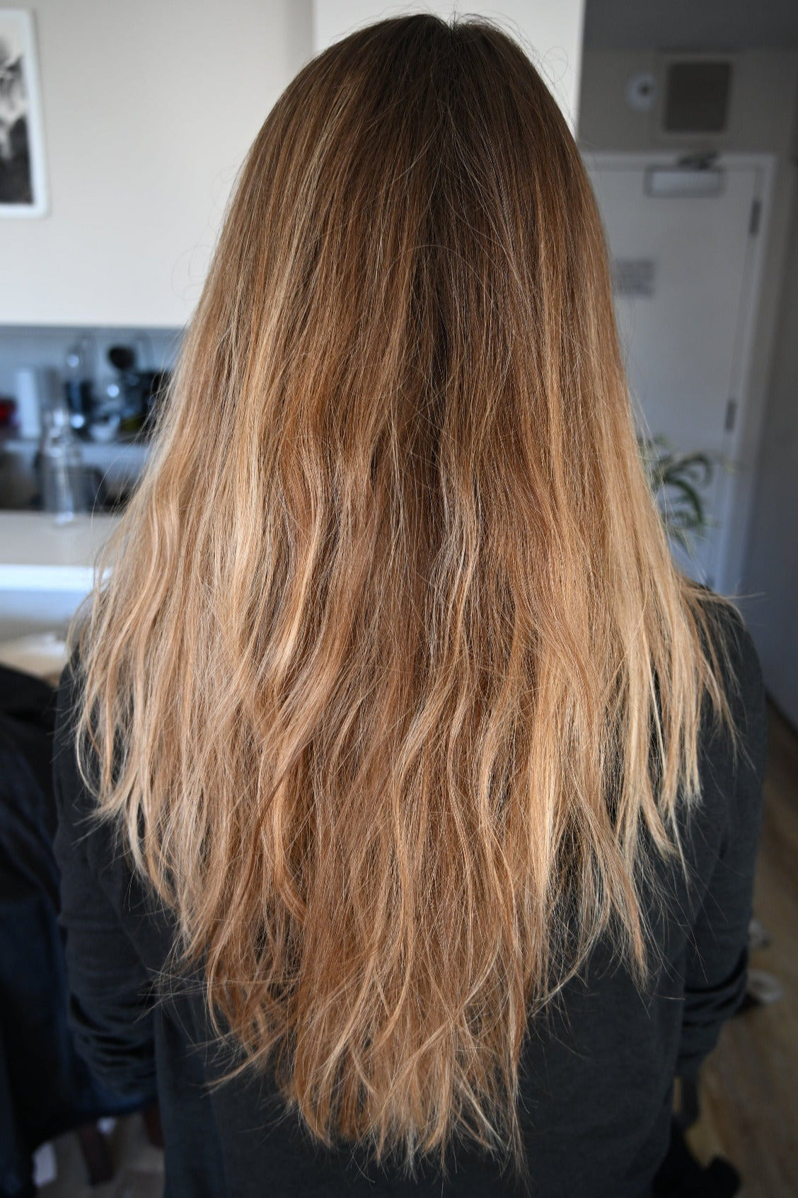 Person with long, wavy blonde hair in a kitchen setting